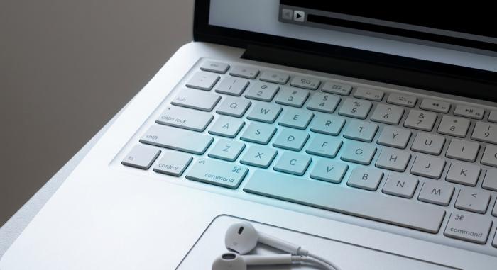 Fotografía aérea de un teclado de laptop de aluminio plateado con las teclas Comando, Shift, 3, 4 y 5 sutilmente resaltadas con un suave brillo azul.